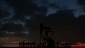 Silhouette of crude oil pump in the oilfield on a beautiful cloudy sunset background