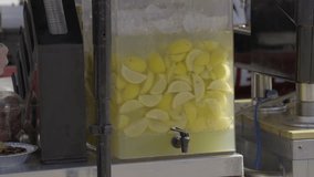 This video shows a close up view of a commercial lemonade dispenser at an outdoor food stall on a sunny day.