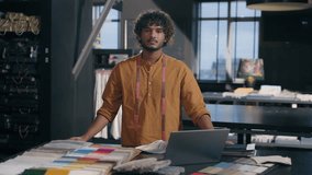 Indian Arabian man happy smiling creative designer fashion clothing tailor posing crossed hands in modern studio textile workshop with fabric color swatches for interior design project small business - Powered by Shutterstock - Get 15% off with code: PIKWIZARD15