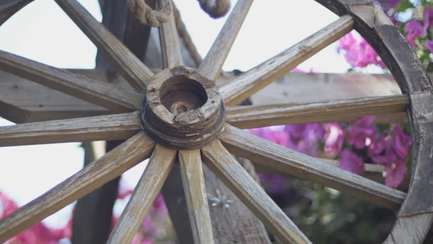 Old wooden wheel with wooden spokes. Wooden object close up.