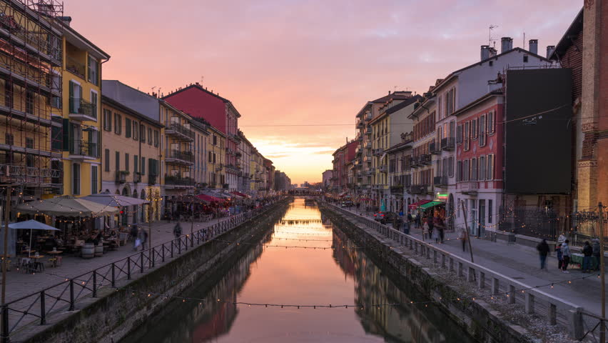 Naviglio Canal in Milan, Italy with a dramatic golden hour sky.