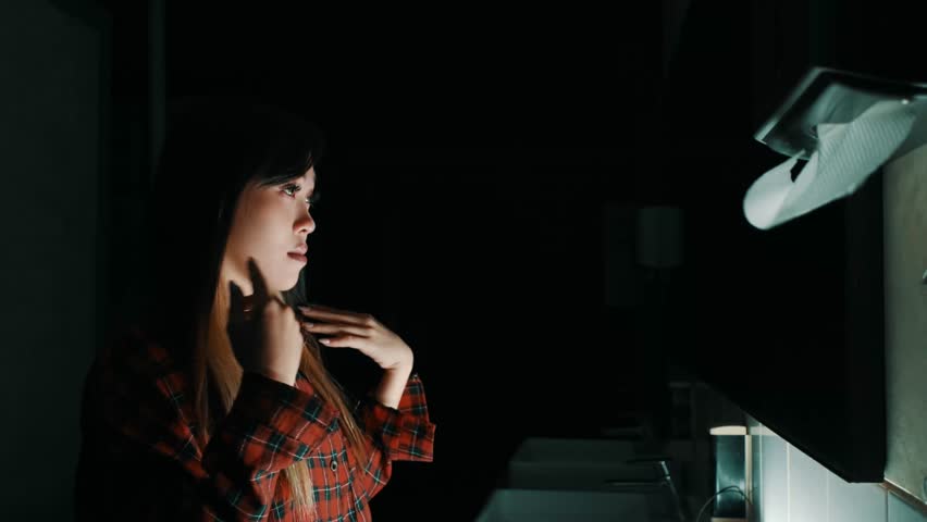 Person in dark room with hands pressed against a bright computer screen, depicting late-night work or internet browsing during the night