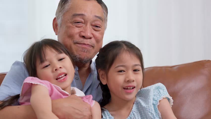 Happy Asian senior grandfather sits on a couch with his granddaughter and plays with his granddaughter in the living room at home, The Concept of family having fun in their house Royalty-Free Stock Footage #3437662795