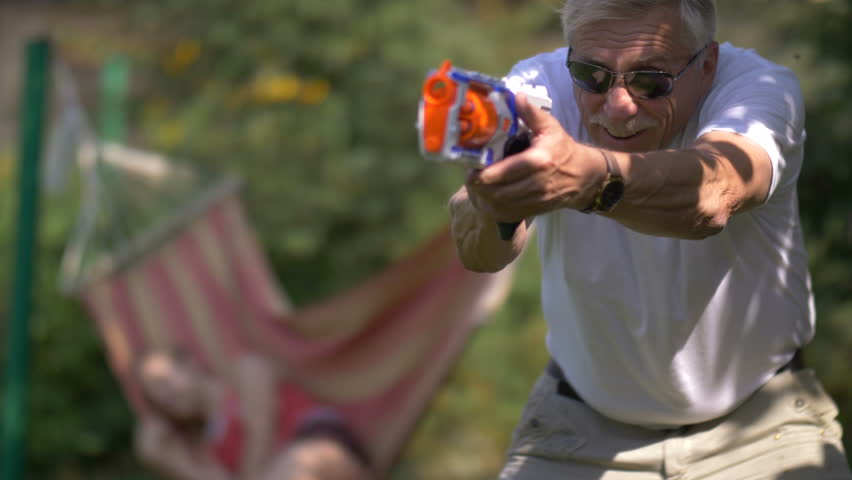 Senior man playing with a toy gun fight on nature