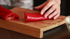 culinary finesse: woman hands cutting fresh red bell peppers on wooden board close-up