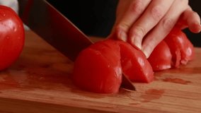 woman hand cutting fresh organic tomatoes into cubes close-up on wooden board