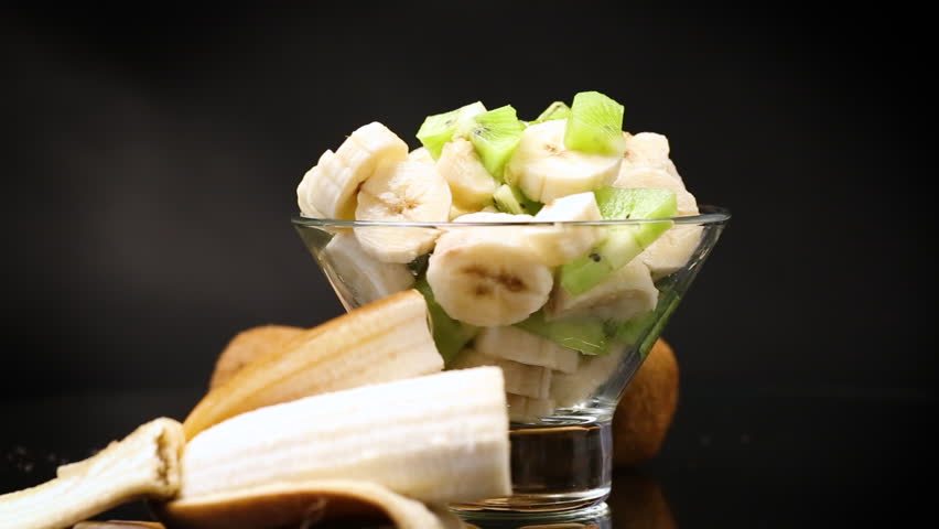 fruit salad of bananas and kiwi isolated on black background