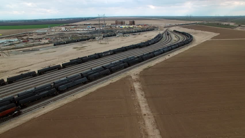 Aerial Shot Of Freight Trains On Tracks Of Rail Yard Drone Flying Backwards Over Tranquil Landscape - Bakersfield, California