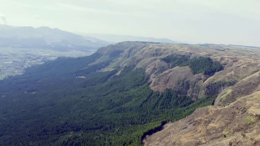 drone video capturing the majestic expanse of the Aso Caldera, one of the largest calderas in the world, located in the heart of Kumamoto Prefecture, Kyushu, Japan. 