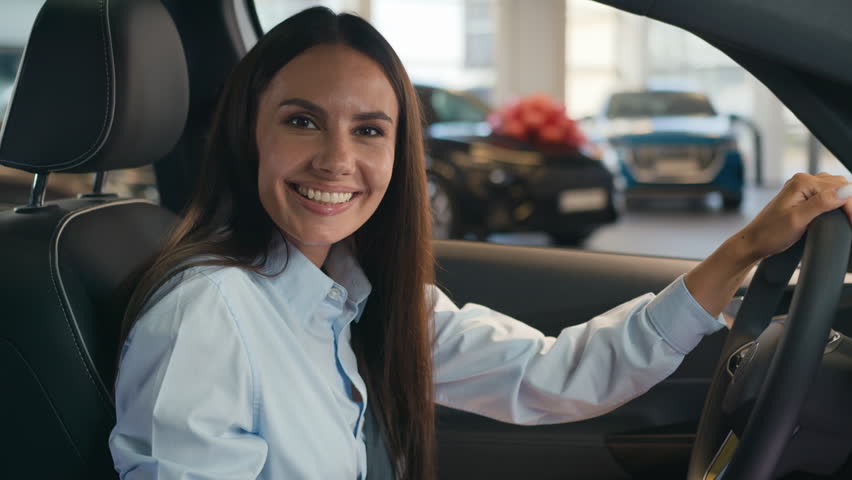 Happy smiling carefree cheerful Caucasian female driver inside car in automobile woman girl lady smile at camera portrait enjoy auto buying new transport buy vehicle rent service rental test drive