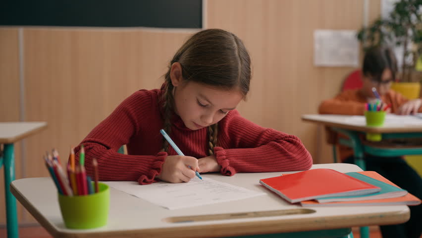 Caucasian clever happy little girl school test study task exam writing notes class lesson learn write copybook kid schoolgirl child pupil studying learning primary education smiling at camera at desk Royalty-Free Stock Footage #3437908377