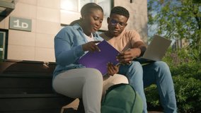 Two African students high school pupils girl guy in college campus outdoors in city park outside on bench discuss topics together task prepare for university test or exams use laptop education study - Powered by Shutterstock - Get 15% off with code: PIKWIZARD15