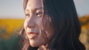Closeup face of Asian woman opening eyes on sunset background. Young female looking straight at the sunflower field landscape. - Powered by Shutterstock - Get 15% off with code: PIKWIZARD15