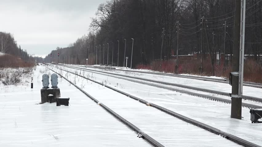 Liepa, Latvia - February 13, 2024 - a snowy train station platform with multiple railway tracks extending into the distance, benches, and overhead wiring.