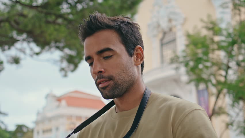 Closeup photographer shooting town street view at summer weekend. Young reporter taking picture beautiful cityscape on professional camera. Handsome unshaven man tourist photographing city landmarks.