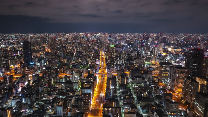 Forwards fly above evening metropolis. Hyperlapse footage of modern large city with high rise buildings. Osaka, Japan