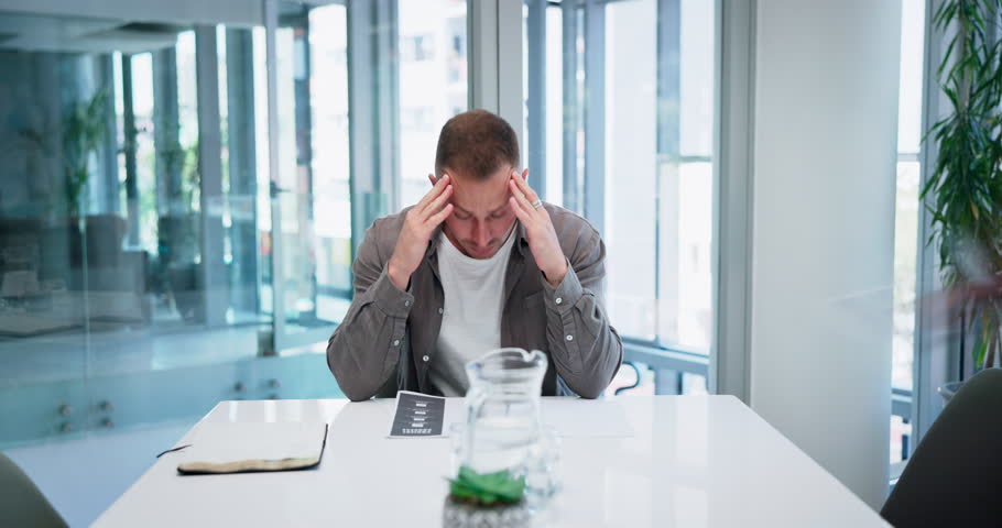 Overwhelmed businessman with headache, burnout or stress with crisis, fatigue or depression in office. Time lapse, blurry or employee with anxiety and frustrated by migraine pain, risk or mistake