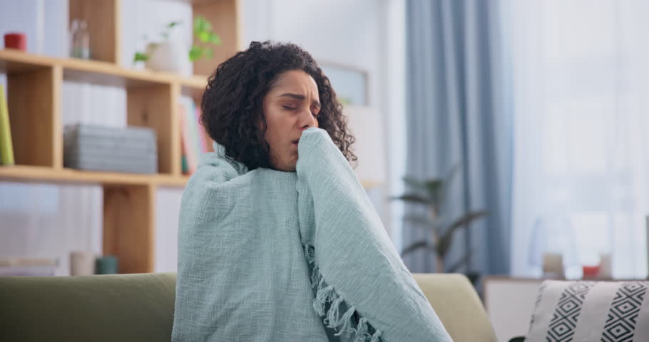 Home, sick and cough with woman, blanket and breathing problem of lungs in a living room. Person, apartment and girl with chest pain and illness with sore throat and tuberculosis with covid and risk