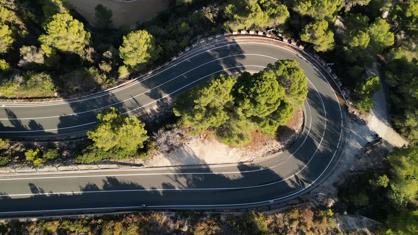 Aerial drone footage of cyclists riding bicycles on an asphalt road on La Fustera Pass. Athletes wearing cycling kits and helmets. Active concept of travel by bicycle. Calp, Alicante, Spain