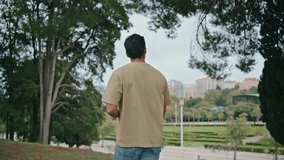 Happy tourist walking park alone back view. Young carefree man looking green garden beauty at weekend stroll. Attractive relaxed guy enjoying summer vacation watching cityscape. Calm leisure concept. - Powered by Shutterstock - Get 15% off with code: PIKWIZARD15