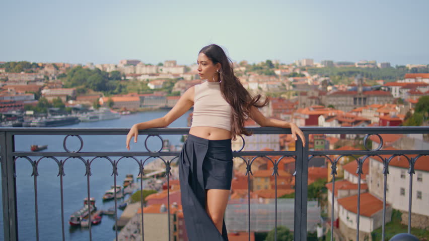 Sexy brunette standing overview bridge posing at sunny summer day zoom on. Seductive confident woman looking camera turning to river view. Relaxed long haired lady enjoying windy weather travelling
