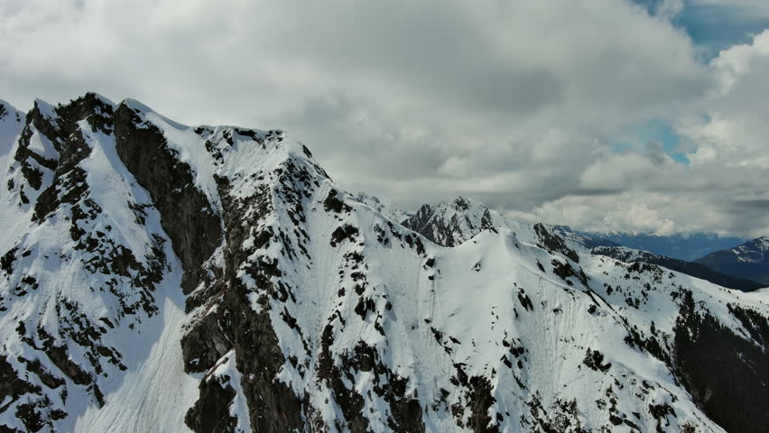 Aerial around view of snow mountain range landscape with clouds. Alps mountains, Austria, 4k