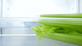 4k video of happy smiling woman taking celery from refrigerator