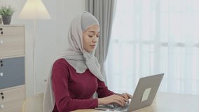 Muslim Islam woman wearing hijab  working on laptop on desk table at home. Entrepreneur woman working for her business at living room home. Business work home concept. - Powered by Shutterstock - Get 15% off with code: PIKWIZARD15
