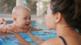Happy toddler at the swimming pool splashing water. Mother holding infant baby son. Active parent, swimming lessons in swimming pool. Little boy on summertime vacation. Young mother playing with kid - Powered by Shutterstock - Get 15% off with code: PIKWIZARD15