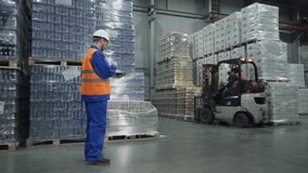 Logistics supervisor uses calculator to count stored items at warehouse. Logistics supervisor moves pallet truck for cargo handling at warehouse. Logistics supervisor checking supply at warehouse - Powered by Shutterstock - Get 15% off with code: PIKWIZARD15