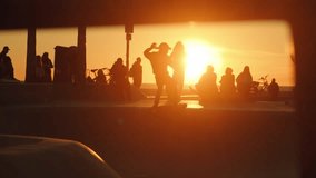 Silhouettes of skateboarders hanging out and riding skateboards in front of sunset sun at Venice Beach skate park in Los Angeles, California. Slow motion shot. - Powered by Shutterstock - Get 15% off with code: PIKWIZARD15