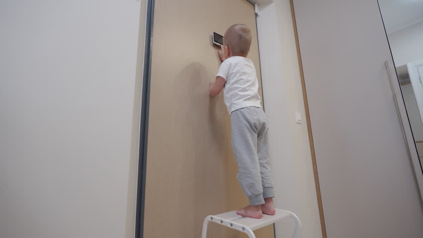 child little boy looking through intercom screen of door peephole surveillance camera on entrance door. Home security and video surveillance. Device to see the person behind the door.