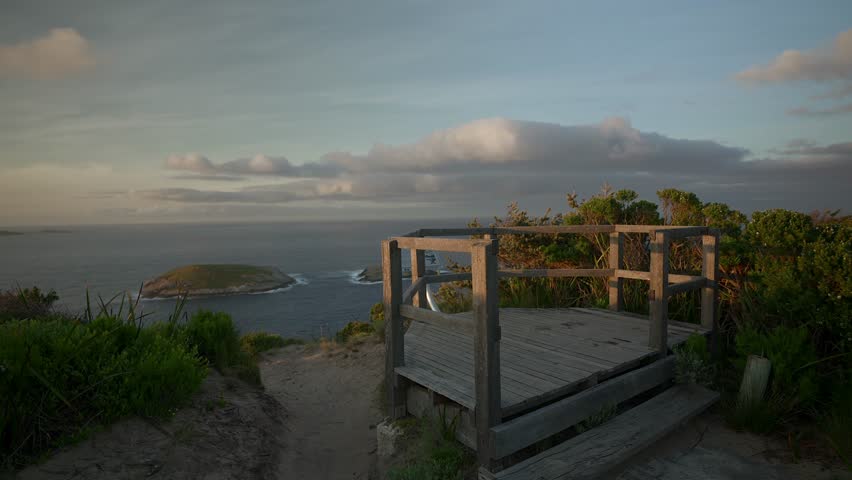 A man walks up onto a wooden lookout platform, admiring the view before walking off camera.