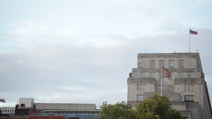 Traveling view of underneath Waterloo Bridge with buildings in background in
