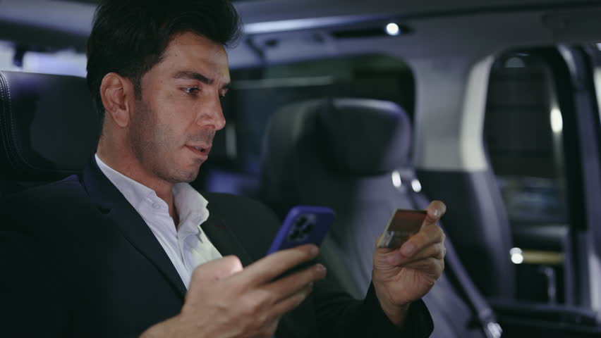 Businessman Sitting in Car Using Smartphone and Holding Credit Card to Pay Bill for Parking Online. Bearded Male in Automobile Buying New Car Detail from Online Store. Technology and Car Concept