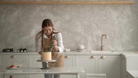 Caucasian woman in the kitchen. woman and cake. woman decorating a cake with cream. slow-motion video. High-quality shooting in 4K format