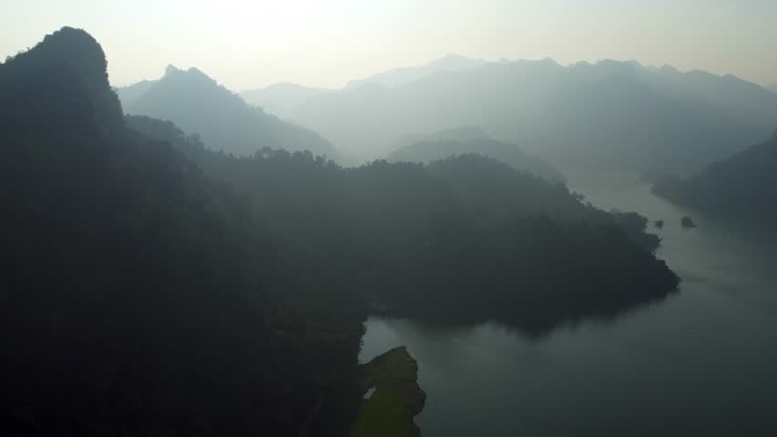 Mist drifts across the surface of the emerald-green waters of Ba Be Lake