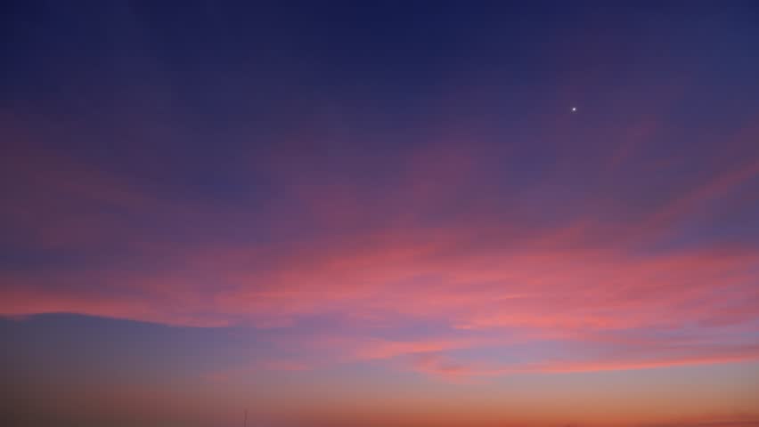 A stunning sunrise timelapse with vibrant hues of red, orange, and purple painting the sky. The blend of colors creates a serene, capturing the beauty and tranquility of the early morning. Time lapse.