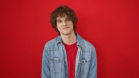 Smiling young man with curly hair wearing denim jacket and red shirt, isolated on red background - Powered by Shutterstock - Get 15% off with code: PIKWIZARD15