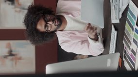 Vertical waist up of young Biracial male interior designer looking at drawing plans and blueprints while sitting by work desk at home office - Powered by Shutterstock - Get 15% off with code: PIKWIZARD15