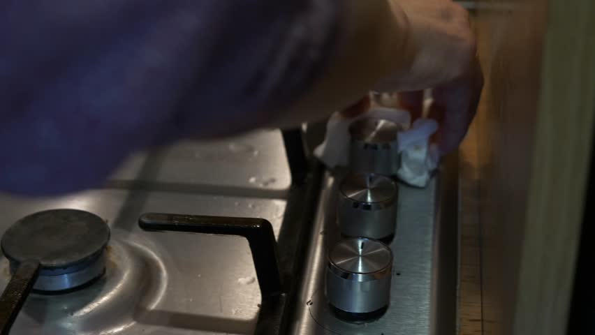 A woman is diligently wiping down a stovetop using a paper tissue to remove dirt and grease, demonstrating a simple household cleaning task. Royalty-Free Stock Footage #3438813431