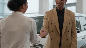 Car dealer woman talk to African American man business client help buying new automobile in showroom auto sale in dealership happy customer and seller handshake successful deal purchase hands shaking - Powered by Shutterstock - Get 15% off with code: PIKWIZARD15