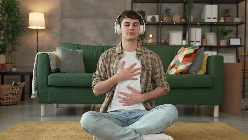 one teenager man young caucasian male use headphones for online guided meditation practice mindfulness yoga with eyes closed at home real people self care manifestation concept copy space generation Z Royalty-Free Stock Footage #3438824597