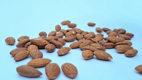 A group of roasted almond falls onto white ground surface. 