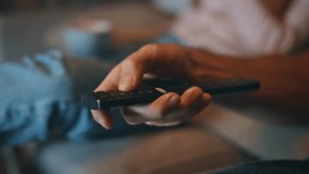 Boyfriend hand holding tv remote at home closeup. Unknown wife warming tea cup at cozy couch. Unrecognized couple choosing television program resting on sofa. Relaxed family watching weekend shows - Powered by Shutterstock - Get 15% off with code: PIKWIZARD15