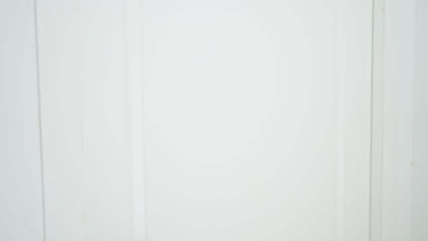 A surprised man with tattoos peeks through a white door, expressing a range of emotions in a home setting.