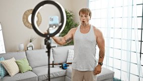 Young blond man with beard filming workout in a modern living room with ring light