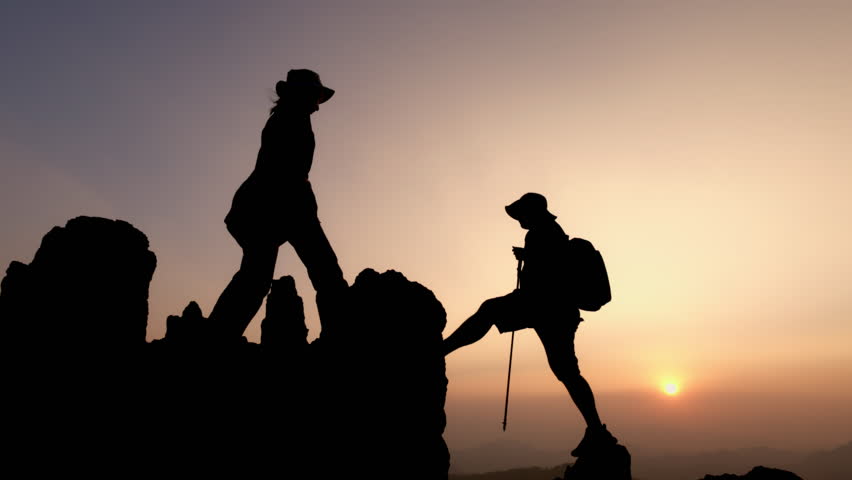 silhouette male and female hikers climbing up mountain cliff. helps and team work concept. Independent hiking travel, success. Royalty-Free Stock Footage #3438963185