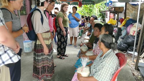 BANGKOK, THAILAND, JULY 15, 2017: A group of young people on a short-term missions trip hands out bags of rice to elderly people living in the slums of Bangkok, Thailand.