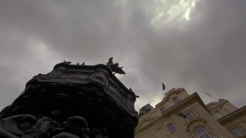 Birds flying and landing on the famous Eros statue in London